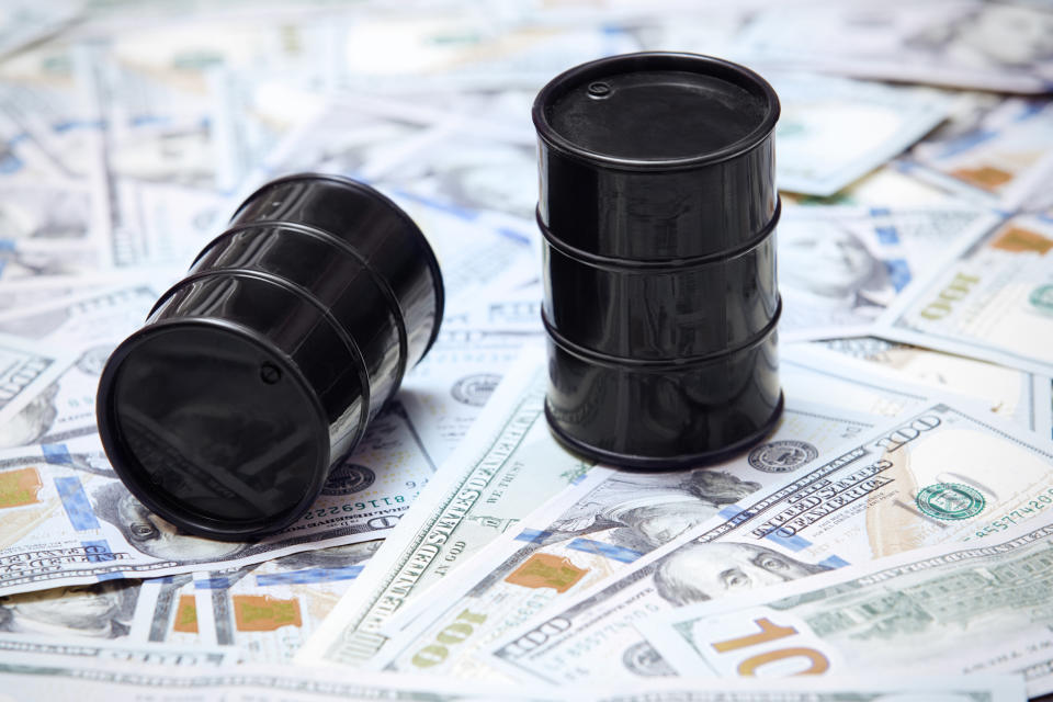 Two oil barrels on top of U.S. currency.