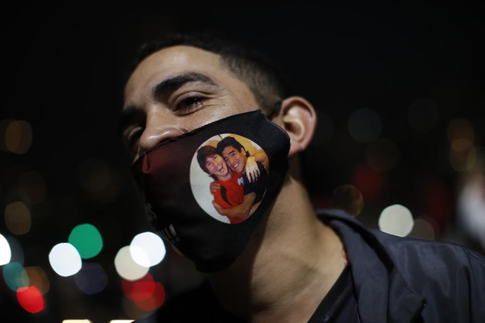 A Newell's Old Boys soccer club fan wears a stylized protective mask featuring soccer legends Leonel Messi and Diego Maradona, during a caravan in Messi's hometown, in Rosario, Argentina, Thursday, Aug. 27, 2020. Fans hope to lure him home following his announcement that he wants to leave Barcelona F.C. after nearly two decades with the Spanish club. (AP Photo/Natacha Pisarenko)