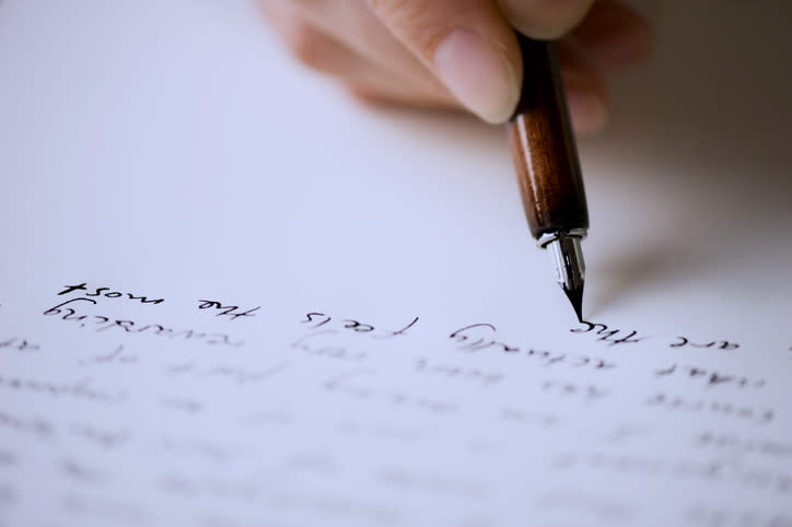 Close-up of a hand writing with a fountain pen on paper with cursive text