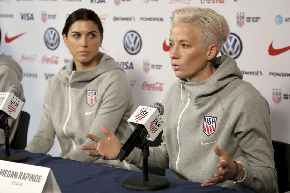 FILE - United States women's national soccer team member Alex Morgan, left, listens as teammate Megan Rapinoe speak to reporters during a news conference in New York, Friday, May 24, 2019. Megan Rapinoe and Alex Morgan were included on the U.S. national team roster for the upcoming CONCACAF W Championship, which will determine four of the region’s teams in the 2023 Women’s World Cup. (AP Photo/Seth Wenig, File)