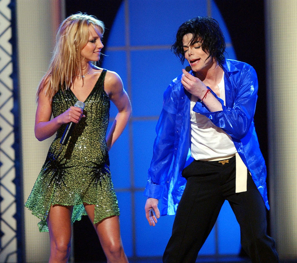 Britney Spears in a green dress and Michael Jackson in a blue shirt and black pants performing on stage together