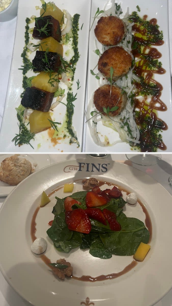 Two white plates with gourmet appetizers and a main course salad topped with strawberries, cheese, and nuts, served at GW Fins restaurant