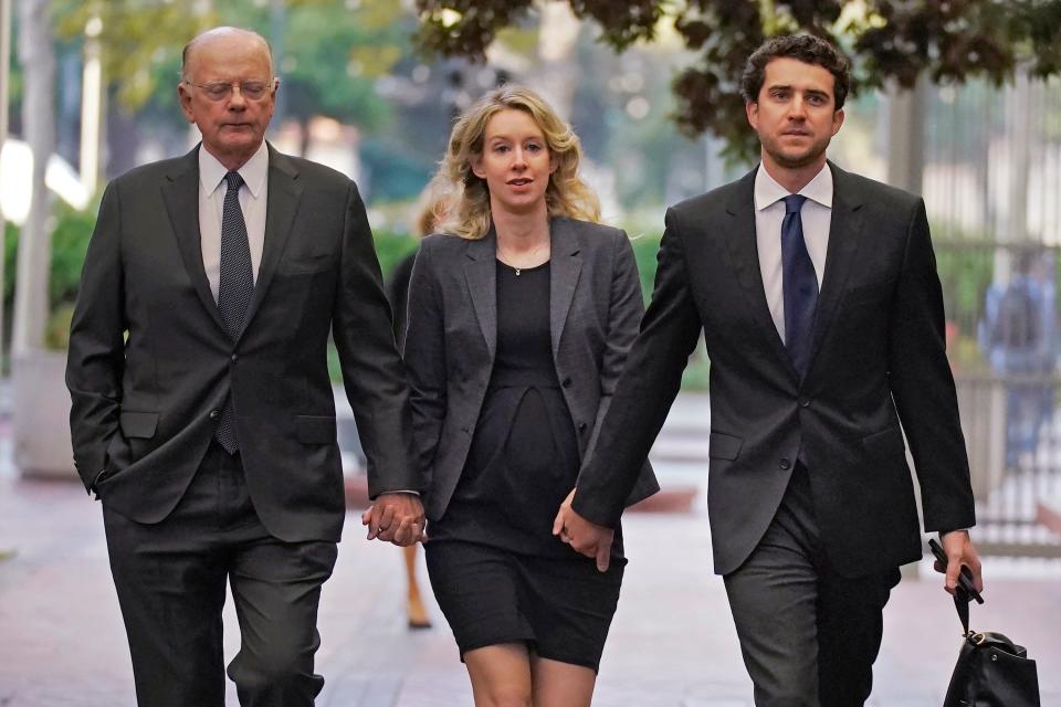 Former Theranos CEO Elizabeth Holmes, center, arrives at federal court with her father, Christian Holmes IV, left, and partner, Billy Evans, in San Jose, Calif., on Oct. 17, 2022. She has given birth to her second child and wants to defer imprisonment as she appeals her fraud conviction.