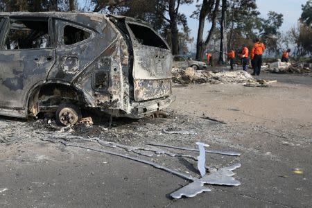 Search and rescue personnel inspect the aftermath of the Tubbs Fire behind a destroyed car in the Coffey Park neighborhood of Santa Rosa, California U.S., October 17, 2017. REUTERS/Loren Elliott