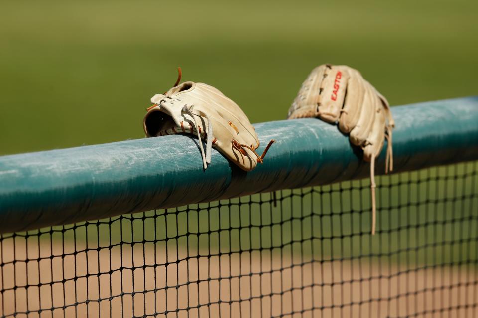 Gloves sit on the dugout wall during a softball  game.