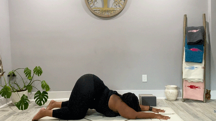 Woman on your knees on her yoga mat with her arms alongside her ears and her chest lowered toward the mat with a slight backbend