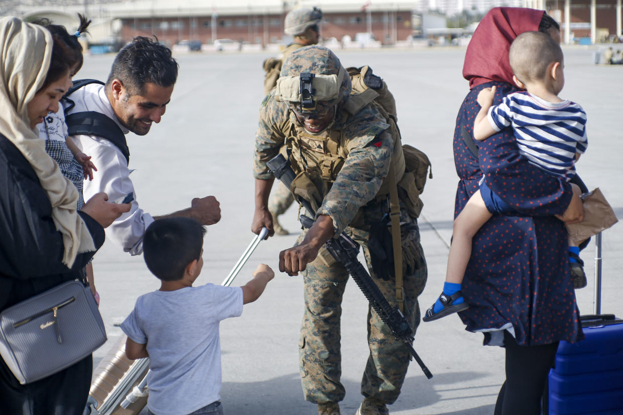 A U.S. Marine assigned to 24th Marine Expeditionary Unit fist bumps a child evacuee during a military drawdown at Hamid Karzai International Airport, Afghanistan, on August 18, 2021.  (Lance Cpl Nicholas Guevara/USMC/UPI/Shutterstock)