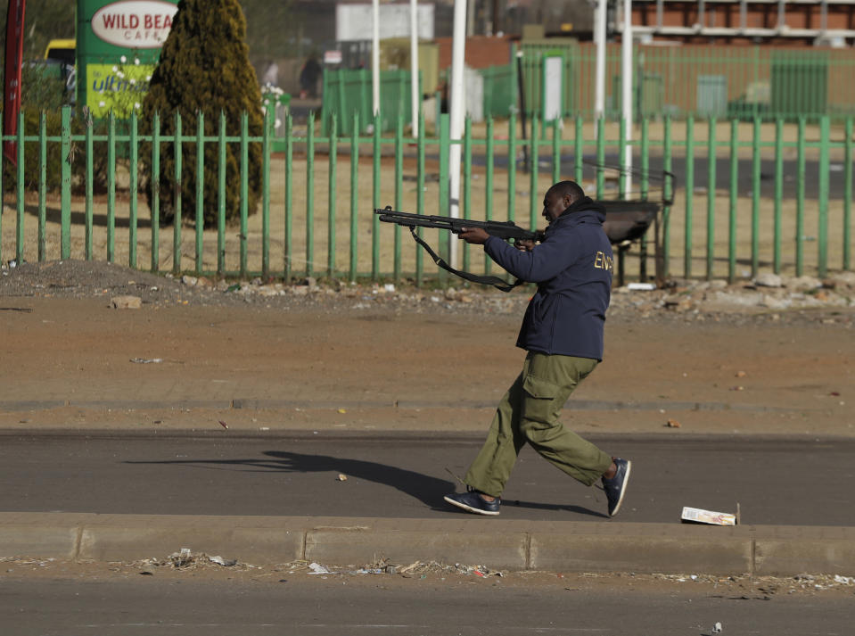 A security man takes aim at looters at a shopping centre in Soweto, Johannesburg, Tuesday July 13, 2021. South Africa's rioting continued Tuesday with the death toll rising to 32 as police and the military struggle to quell the violence in Gauteng and KwaZulu-Natal provinces. The violence started in various parts of KwaZulu-Natal last week when Zuma began serving a 15-month sentence for contempt of court. (AP Photo/Themba Hadebe)