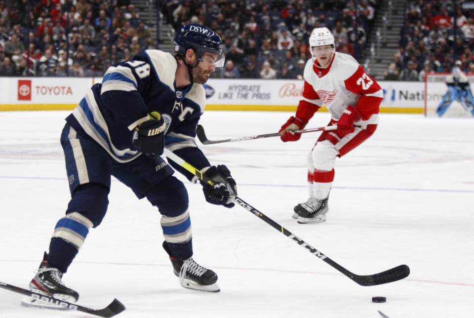 Columbus Blue Jackets forward Boone Jenner, left, controls the puck in front of Detroit Red Wings forward Lucas Raymond during the second period of an NHL hockey game in Columbus, Ohio, Monday, Nov. 15, 2021. (AP Photo/Paul Vernon)