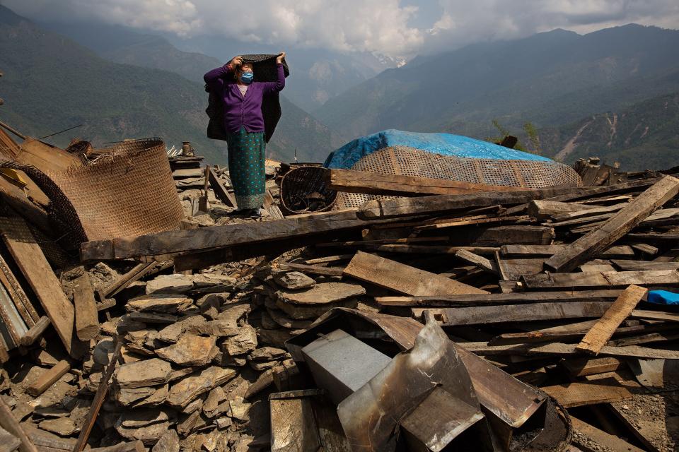 Nepal earthquake. Barpak, the epicenter of the earthquake. Funeral of Pur Bahadur Gurung, 26, who had just been dug out of the rubble. Saainli Gurung, his mother weeping. Scenes of villagers salvaging building materials and personal possessions. Dhan Raj Ghale, 30, dressed in mourning garb after the death of his wite, salvaging buildings materials and possessions from his house. by James Nachtwey