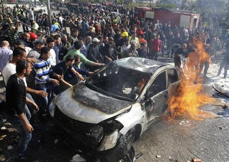 Civil defence members and civilians put out a fire at the site of an explosion in the southern suburbs of Beirut February 19, 2014. REUTERS/Issam Kobeisi