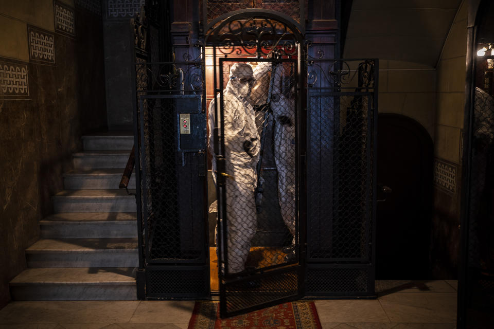 Wearing protective suits to prevent infection, mortuary workers move the body of an elderly person who died of COVID-19 from an elevator after removing it from a nursing home in Barcelona, Spain, Nov. 13, 2020. The image was part of a series by Associated Press photographer Emilio Morenatti that won the 2021 Pulitzer Prize for feature photography. (AP Photo/Emilio Morenatti)
