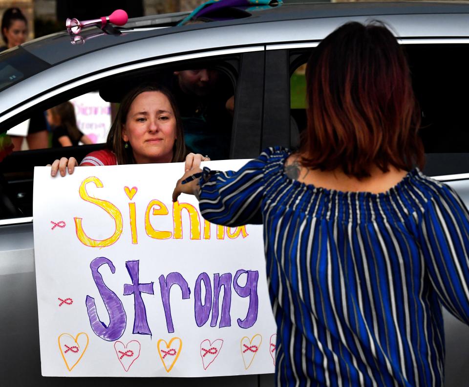 A participant gives a homemade sign to the Molina family as she pauses during Tuesday's parade.