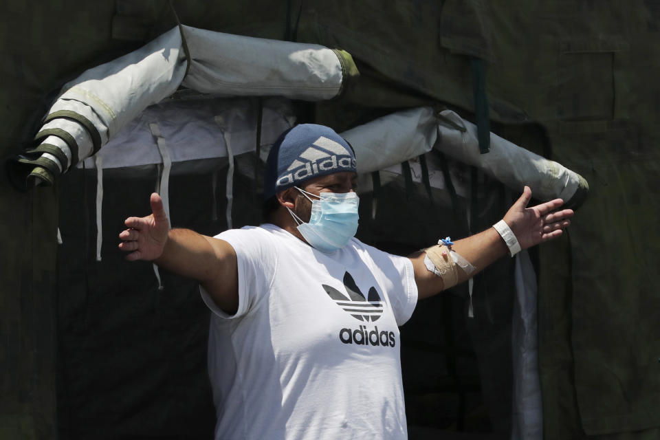 A COVID-19 patient does breathing exercises at the entrance of a tent set up to treat new coronavirus cases outside the Social Security Hospital, shortly before being released in Quito, Ecuador, Thursday, April 22, 2021. The government decreed new lockdown rules on April 21 for the majority of Ecuador's provinces, limiting movement on weeknights and an all-day curfew on weekends to curb the spread of the new coronavirus which is overwhelming hospitals. (AP Photo/Dolores Ochoa)