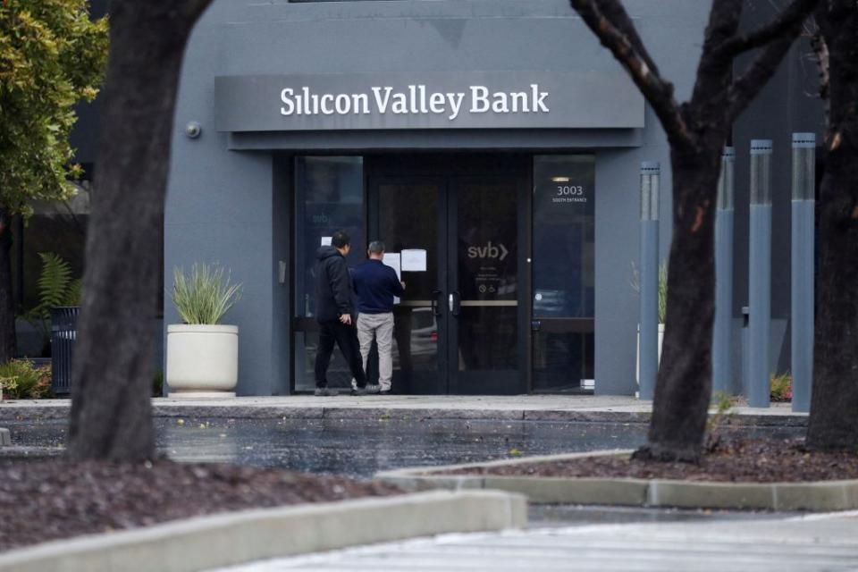 美國矽谷銀行宣布關閉進行清算，銀行人員在門上貼上告示，旁邊則有一名男子關心查看告示內容。（路透）