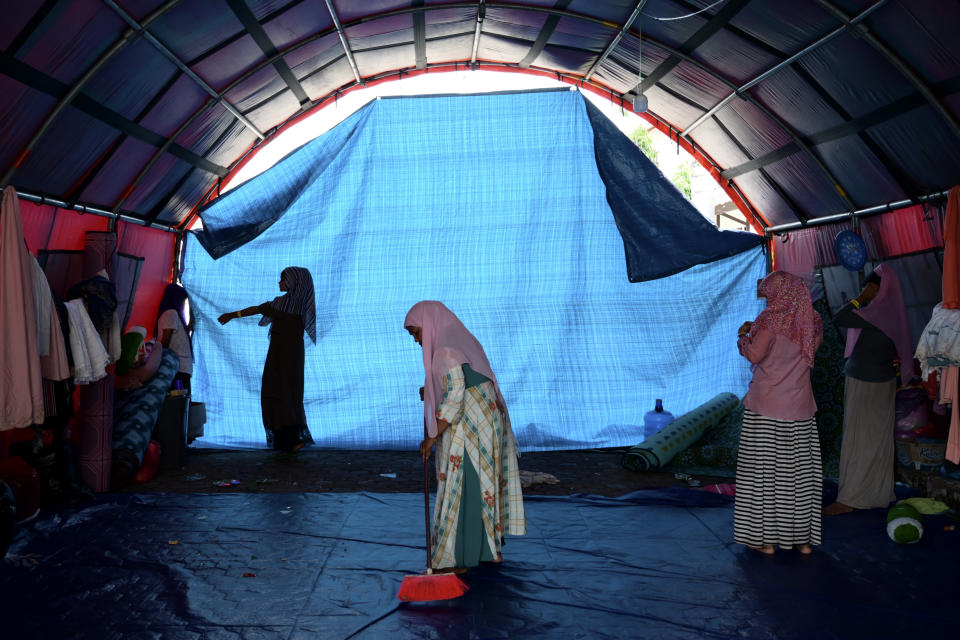 Fatima Khatun, a Rohingya survivor of a capsized refugee boat, cleans her temporary shelter in Meulaboh, Indonesia, on Wednesday, April 3, 2024. Fatima was among 75 people rescued in March from atop the overturned hull of the boat, which capsized off Indonesia's coast. Dozens of others, including Fatima's 8-year-old daughter, died. (AP Photo/Reza Saifullah)