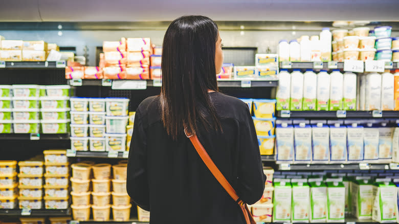 Person surveying shelves of butter at grocery store