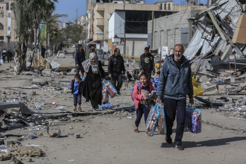 Palestinians walk with their belngings amid the devastation caused by the Israeli bombing on the Nuseirat refugee camp, after the withdrawal of Israeli forces from the area. Mohammed Talatene/dpa