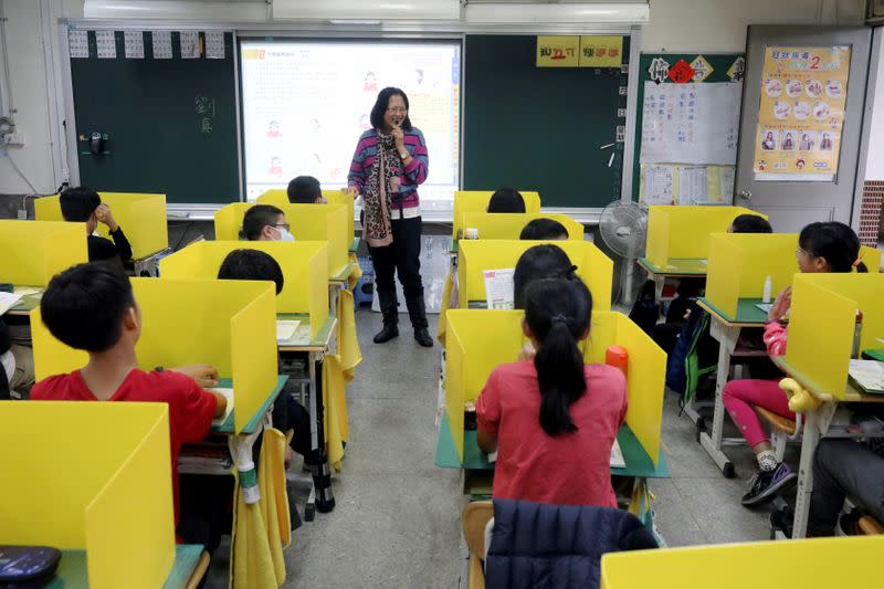 Pupils sit in desks with yellow dividers at Dajia Elementary school in Taipei