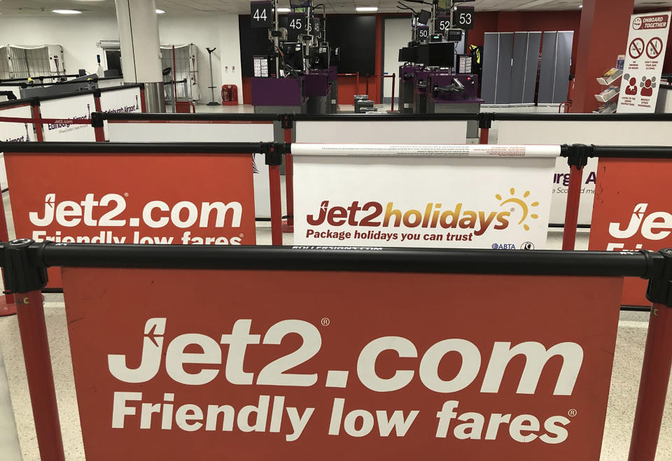 Empty check-in desks at the Jet2 desk at Edinburgh Airport, Scotland, Saturday March 14, 2020. British budget airline Jet2 apparently turned back in midair all its planes bound for Spain on Saturday as it announced the cancellation of all its flights to the country. (Andrew Milligan/PA via AP)