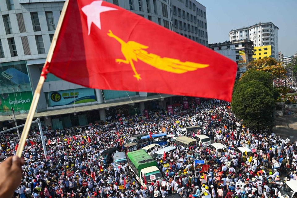 A protester waves the National League for Democracy (NLD) flag while others take part in a demonstration against the military coup in Yangon last yea (AFP via Getty Images)