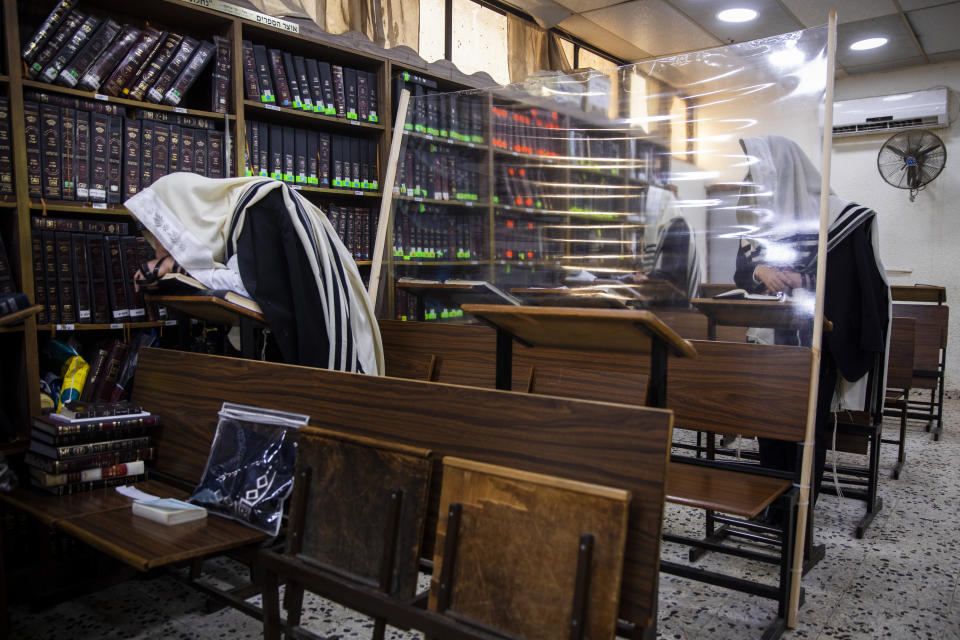 Ultra-Orthodox Jews pray in a synagogue separated by plastic shields, following new government measures to help stop the spread of the coronavirus, in Bnei Brak, Israel, Friday, Sept 18, 2020. Israel is set to go back into a three-week lockdown later Friday to try to contain a coronavirus outbreak that has steadily worsened for months as its government has been plagued by indecision and infighting. The closures coincide with the Jewish High Holidays, when people typically visit their families and gather for large prayer services. (AP Photo/Oded Balilty)