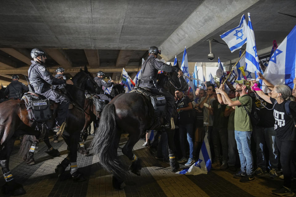 Mounted police disperse demonstrators trying to block the entrance to Israel's main international airport during a protest against plans by Prime Minister Benjamin Netanyahu's government to overhaul the judicial system, at Ben Gurion Airport in Lod, near Tel Aviv, Israel, Monday, July 3, 2023. Thousands of Israelis blocked traffic and snarled movement at the country's main international airport. (AP Photo/Ohad Zwigenberg)