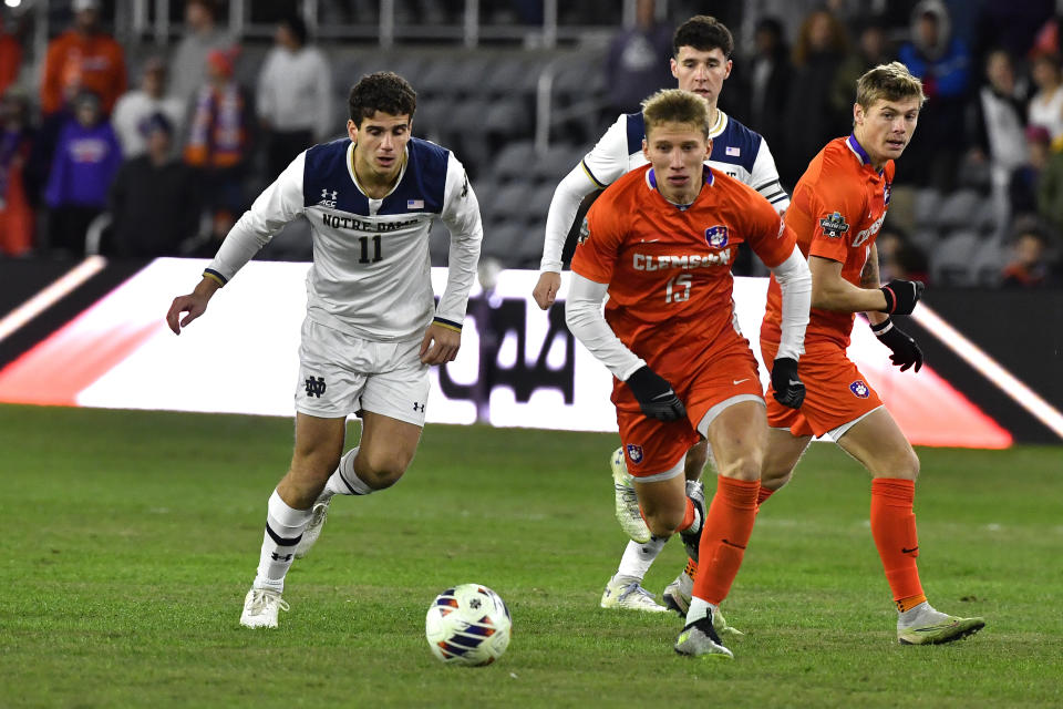 Notre Dame forward Daniel Russo (11) and Clemson midfielder Ousmane Sylla chase the ball during the first half of an NCAA college soccer tournament championship game in Louisville, Ky., Monday, Dec. 11, 2023. (AP Photo/Timothy D. Easley)