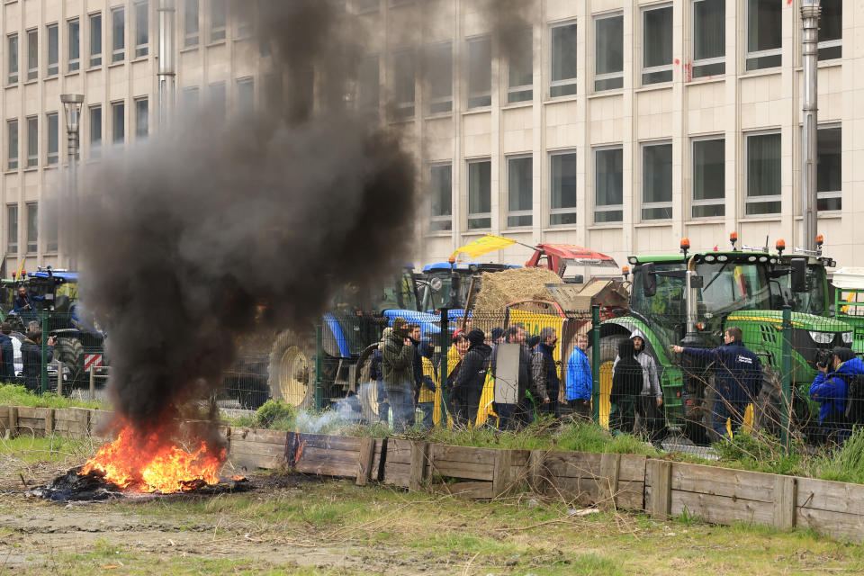 Protestors light fires next to their tractors during a demonstration of farmers near the European Council building in Brussels, Tuesday, March 26, 2024. Dozens of tractors sealed off streets close to European Union headquarters where the 27 EU farm ministers are meeting to discuss the crisis in the sector which has led to months of demonstrations across the bloc. (AP Photo/Geert Vanden Wijngaert)
