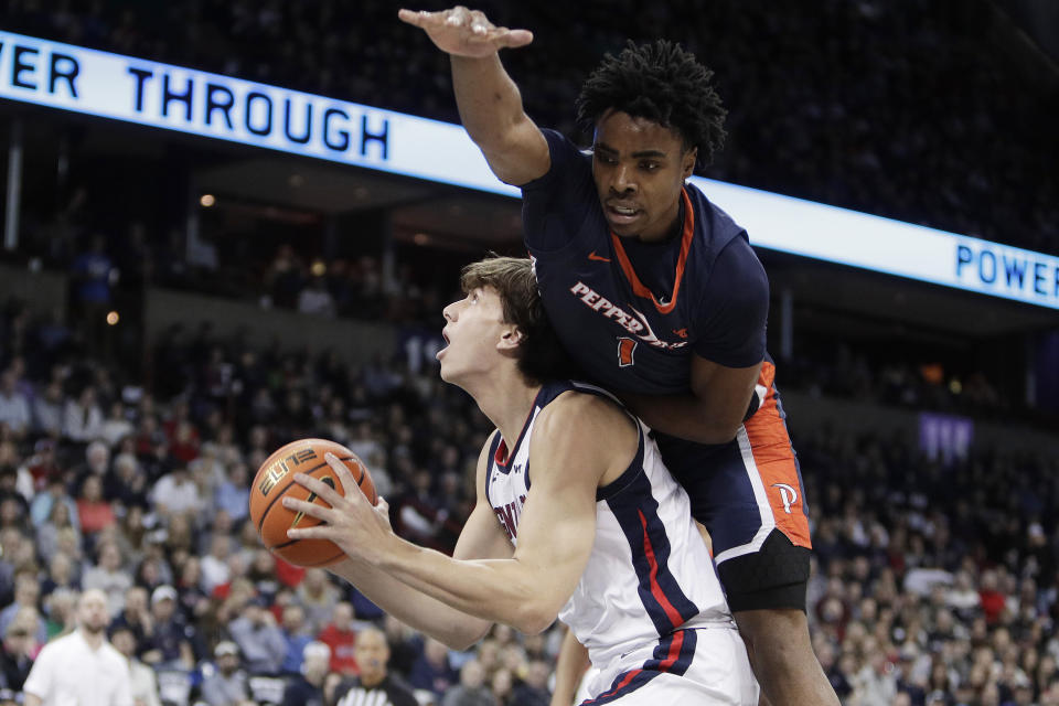 Gonzaga forward Braden Huff, left, drives to the basket while pressured by Pepperdine guard Michael Ajayi (1) during the first half of an NCAA college basketball game Thursday, Jan. 4, 2024, in Spokane, Wash. (AP Photo/Young Kwak)