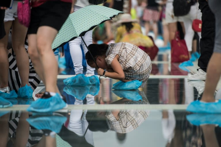 A girl looks through the glass on the world's highest and longest glass-bottomed bridge is seen above a valley in Zhangjiajie in China's Hunan Province on August 20, 2016