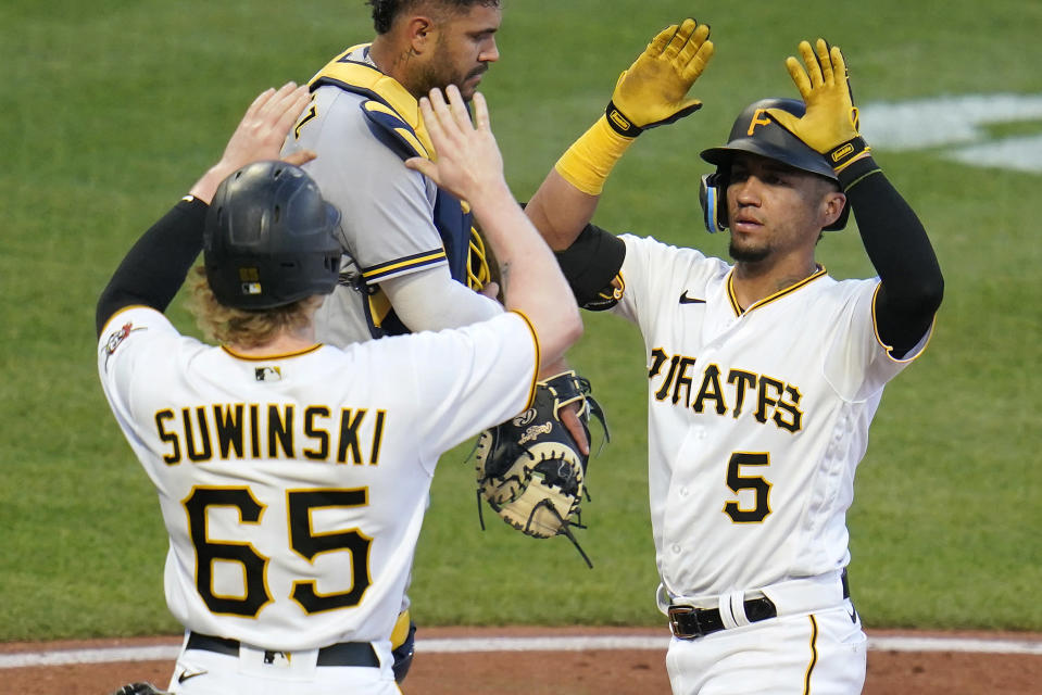 Pittsburgh Pirates' Michael Perez (5) is greeted by Jack Suwinski (65) as he crosses home plate past Milwaukee Brewers catcher Omar Narvaez, center rear, after hitting a two-run home run off relief pitcher Brent Suter during the fourth inning of a baseball game in Pittsburgh, Thursday, June 30, 2022. (AP Photo/Gene J. Puskar)
