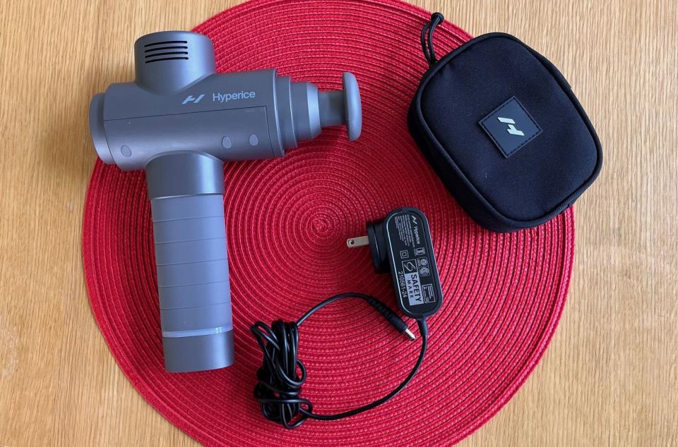 The Hypervolt 2 shown with its AC adapter and attachment carrying case.