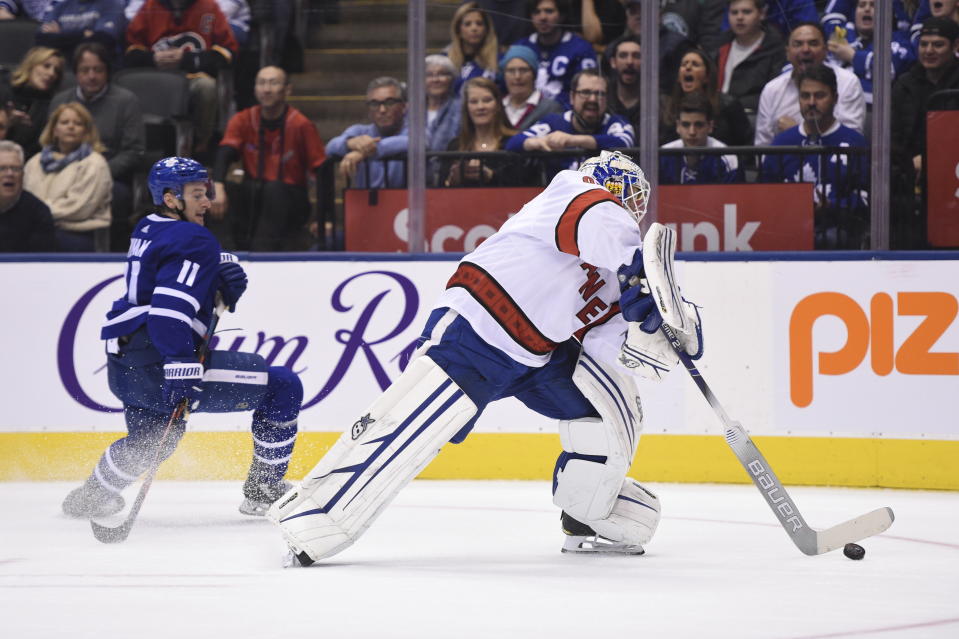 Carolina Hurricanes emergency goalie David Ayres, right, comes out of his net to play the puck against the Toronto Maple Leafs during second-period NHL hockey action in Toronto, Saturday, Feb. 22, 2020. Ayres, who serves as the Toronto Marlies' ice resurfacer driver, replaced Petr Mrazek in-net after a delay in action. (Frank Gunn/The Canadian Press via AP)