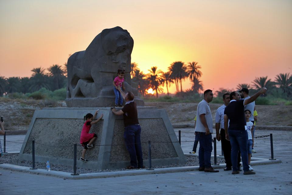 People stand near the Lion of Babylon at the archaeological site of Babylon, Iraq, Friday, July 5, 2019. Iraq on Friday celebrated the UNESCO World Heritage Committee's decision to name the historic city of Babylon a World Heritage Site in a vote held in Azerbaijan's capital, years after Baghdad began campaigning for the site to be added to the list. (AP Photo/Anmar Khalil)