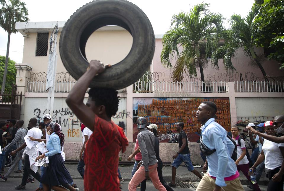 A protester carries a tire to add to a burning barricade during a protest march to demand answers after the kidnapping and murder of high school senior Evelyne Sincère, in Port-au-Prince, Haiti, Thursday, Nov. 5, 2020. The young woman was found in a trash heap Sunday after relatives said they were unable to pay the large ransom demanded by her captors. Human rights groups contend the incident highlights the nation’s worsening security crisis. (AP Photo/Dieu Nalio Chery)
