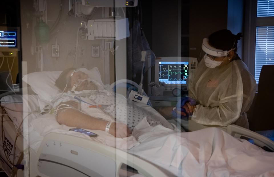 Jennifer holds her dad's hand as she visits him in the ICU.