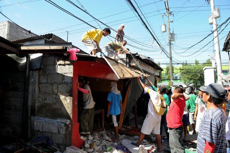 Members of a demolition crew dismantle a house at a slum area in suburban Manila on April 24, 2012. Experts have warned that flooding in Manila has been worsened by the squatter communities who build precarious shanties on the banks of waterways, preventing water from flowing freely and blocking drains with rubbish