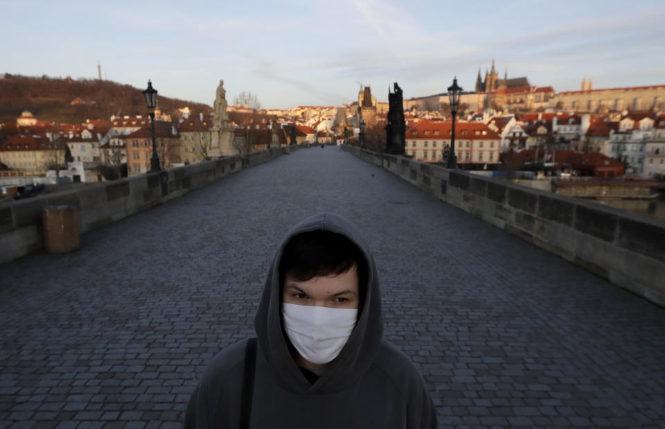 A young man wearing a face mask walks across an empty Charles Bridge in Prague, Czech Republic, Monday, March 16, 2020. The Czech government has imposed further dramatic restrictions on the movement in efforts to contain the outbreak of the coronavirus. Prime Minister Andrej Babis said the government is declaring a quarantine for the entire country, an unprecedented measure in his country's history that became effective on Monday. For most people, the new coronavirus causes only mild or moderate symptoms. For some it can cause more severe illness. (AP Photo/Petr David Josek)