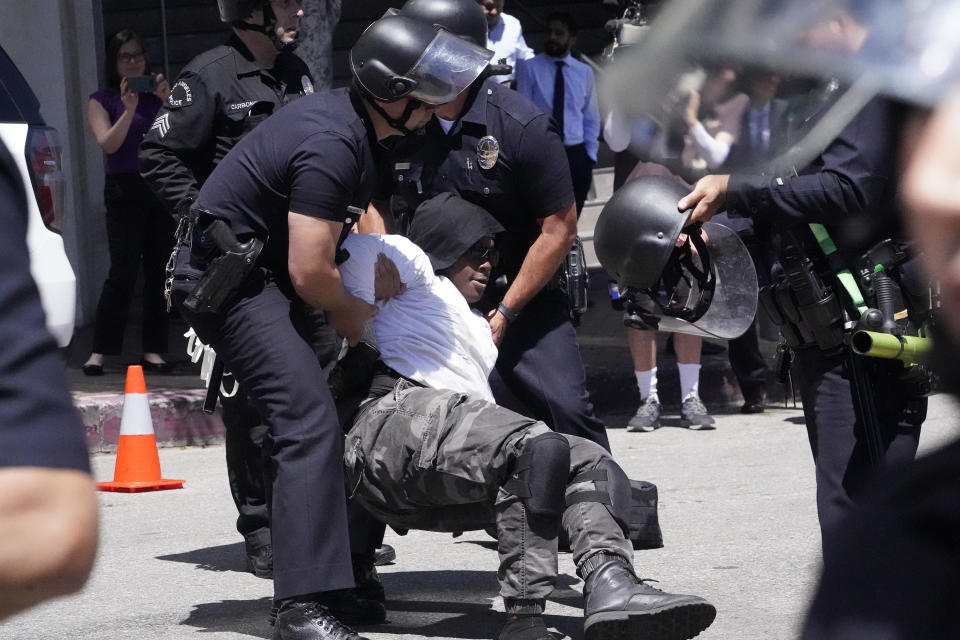 A person is detained by LAPD officers following a surge from police attempting to move a small group of LGBTQ demonstrators away from a Parents Rights sponsored protest nearby Los Angeles Unified School District headquarters, Tuesday, Aug. 22, 2023, in Los Angeles. (AP Photo/Damian Dovarganes)