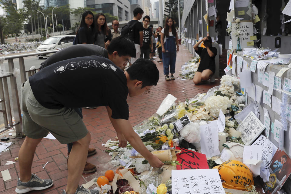 Pro-democracy activist Joshua Wong, second from bottom, and Nathan Law pay respect to a protester who fell to his death after hanging a protest banner against an extradition bill, at a makeshift memorial in Hong Kong, Monday, June 17, 2019. Wong, a leading figure in Hong Kong's 2014 Umbrella Movement demonstrations, was released from prison on Monday and vowed to soon join the latest round of protests. (AP Photo/Kin Cheung)