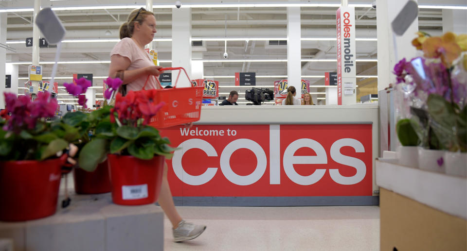 Shopper passes a Coles shopfront.