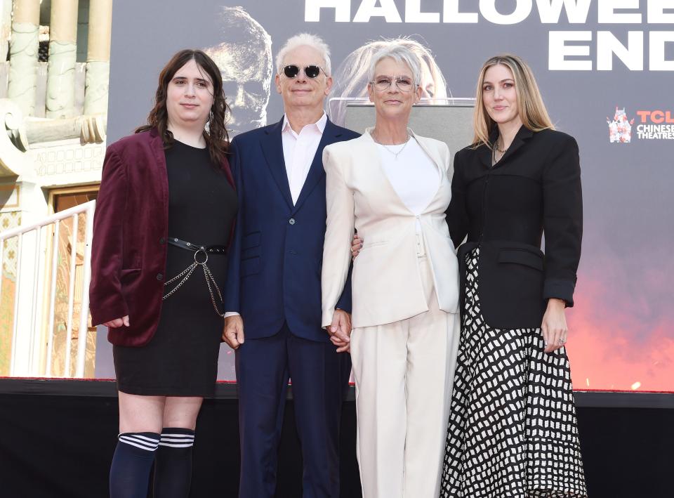 Jamie Lee Curtis in a white suit standing with her husband and two daughters