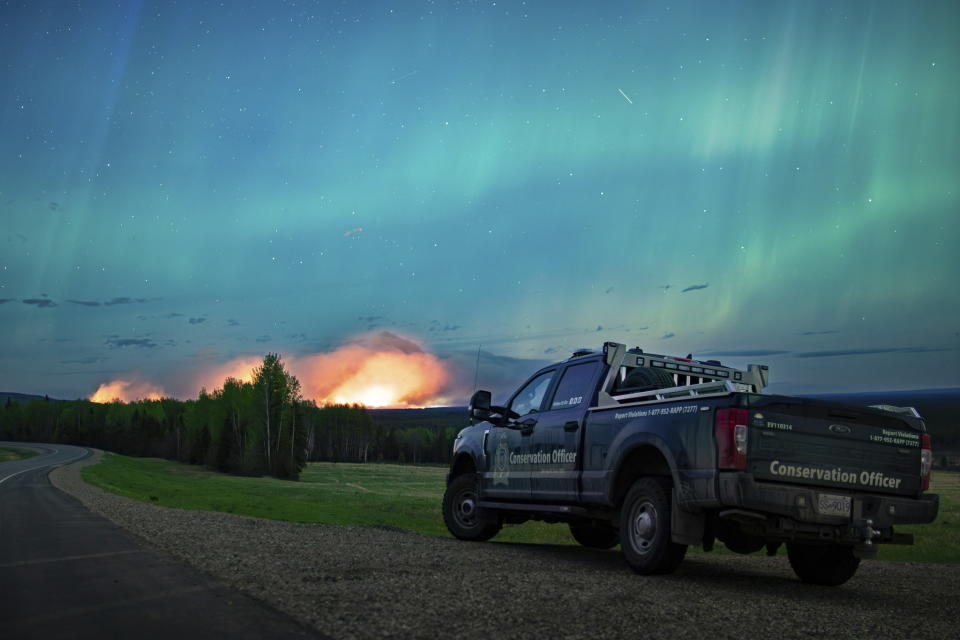 Esta imagen proporcionada por el Ministerio de Agua, Tierras y Gestión de Recursos muestra un incendio forestal, con una aurora boreal sobre él, cerca de Fort Nelson, Canadá, el sábado 11 de mayo de 2024. (Ministerio de Agua, Tierras y Gestión de Recursos/The Canadian Press vía AP)