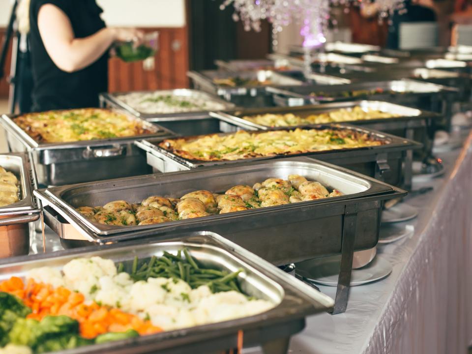 trays of buffet food on white table cloth at wedding