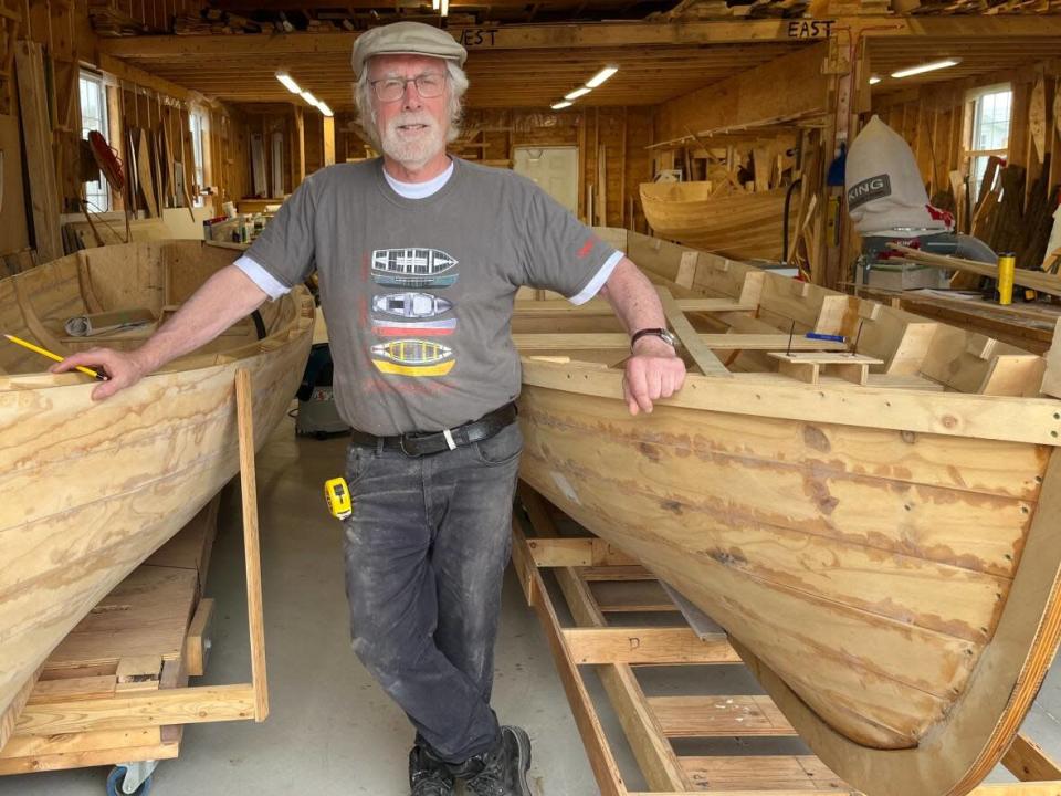 Boat builder Jerome Canning stands next to two wooden punts. He built the one on his right by hand, while the boat on the left is a recreation of the boat on the right made through computer-aided design. (Alex Kennedy/CBC - image credit)
