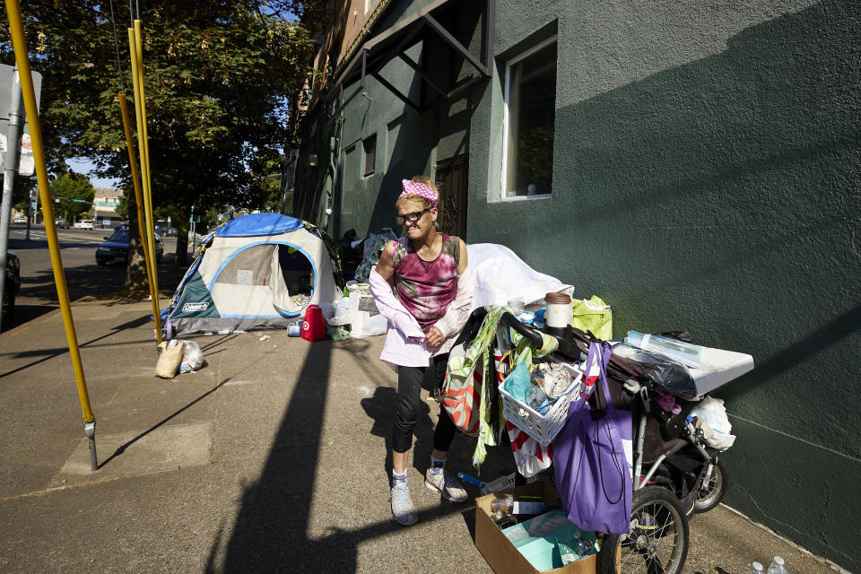 THIS CORRECTS THE NAME OF THE CONTRACTOR TO RAPID RESPONSE BIO CLEAN, NOT RAPID RESPONSE BIO CLEANUP AS ORIGINALLY SENT - Roxanne Simonson, 60, removes her long sleeve shirt after being told by Rapid Response Bio Clean that she has 72 hours to vacant her illegal campsite in Portland, Ore., Thursday, July 27, 2023. Simonson has been homeless for two years. Cities across the U.S. are struggling with and cracking down on tent encampments as the number of homeless people grows, largely due to a lack of affordable housing. Homeless people and their advocates say sweeps are cruel and costly, and there aren't enough homes or beds for everyone. (AP Photo/Craig Mitchelldyer)