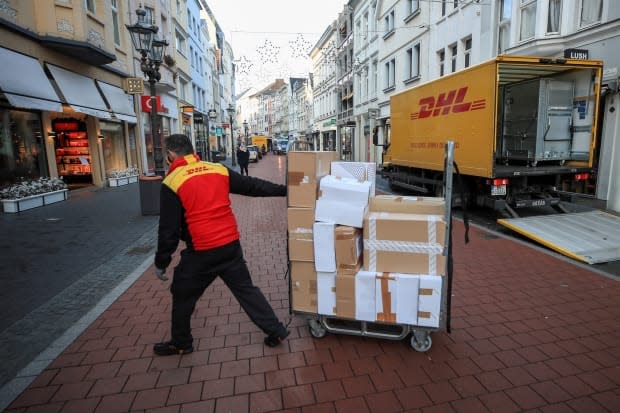 A DHL worker delivers packages in Bonn, Germany, in December 2020. A proposed class-action lawsuit filed in a B.C. court alleges the courier giant requires some customers to pay extra fees by making 'false, misleading and deceptive' claims. (Wolfgang Rattay/Reuters - image credit)
