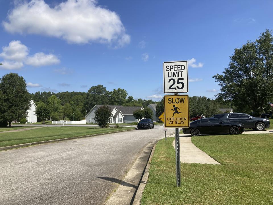 The entrance to the Dogwood Lakes neighborhood in Hampton, Ga., is shown on Sunday, July 16, 2023, with a police car to the left. Police say a man shot and killed four people in the neighborhood on Saturday, July 15, 2023. (AP Photo/Jeff Amy)