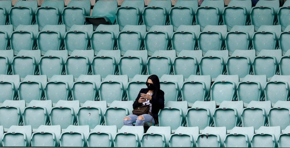 A spectator waits for play to start on day two of the third cricket test between India and Australia at the Sydney Cricket Ground, Sydney, Australia, Friday, Jan. 8, 2021. (AP Photo/Rick Rycroft)